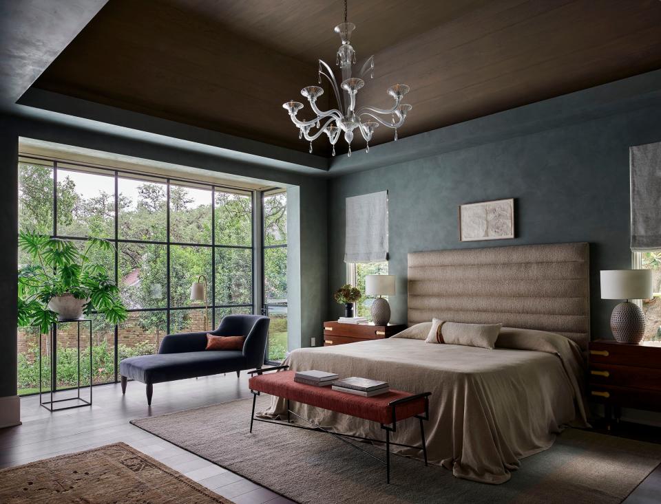 The muted green plaster on the primary suite’s walls complements the vivid colors of the garden, seen through ample steel-framed windows. White oak covers the coffered ceiling. Most of the furniture is custom. The vintage carpets are from Carol Piper Rugs.