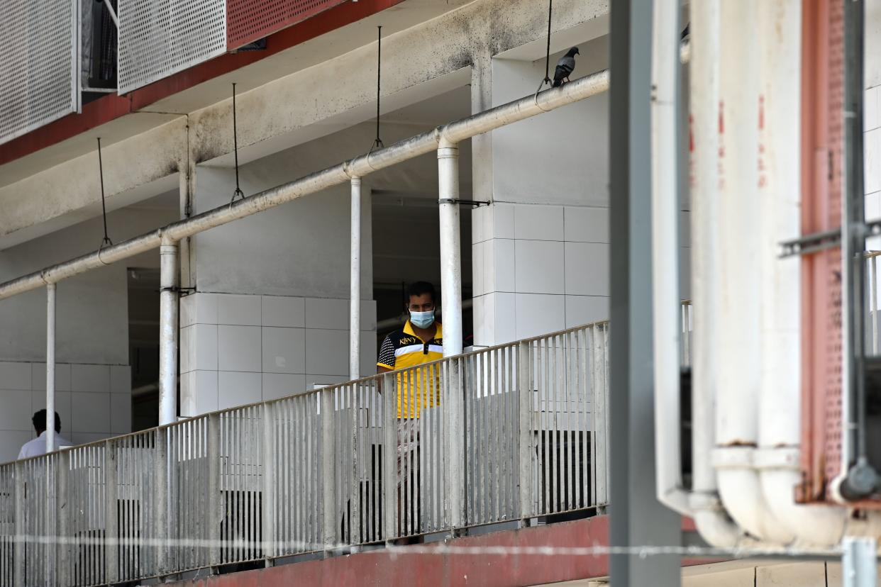 A foreign worker, wearing a face mask, looks out from a window of a workers' dormitory in Singapore on 9 April, 2020. (PHOTO: AFP via Getty Images)