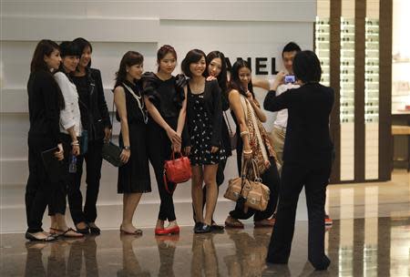 Shoppers pose for a picture in front of a Chanel luxury boutique at the IFC Mall in Shanghai in this June 4, 2012 file photograph. REUTERS/Carlos Barria/Files