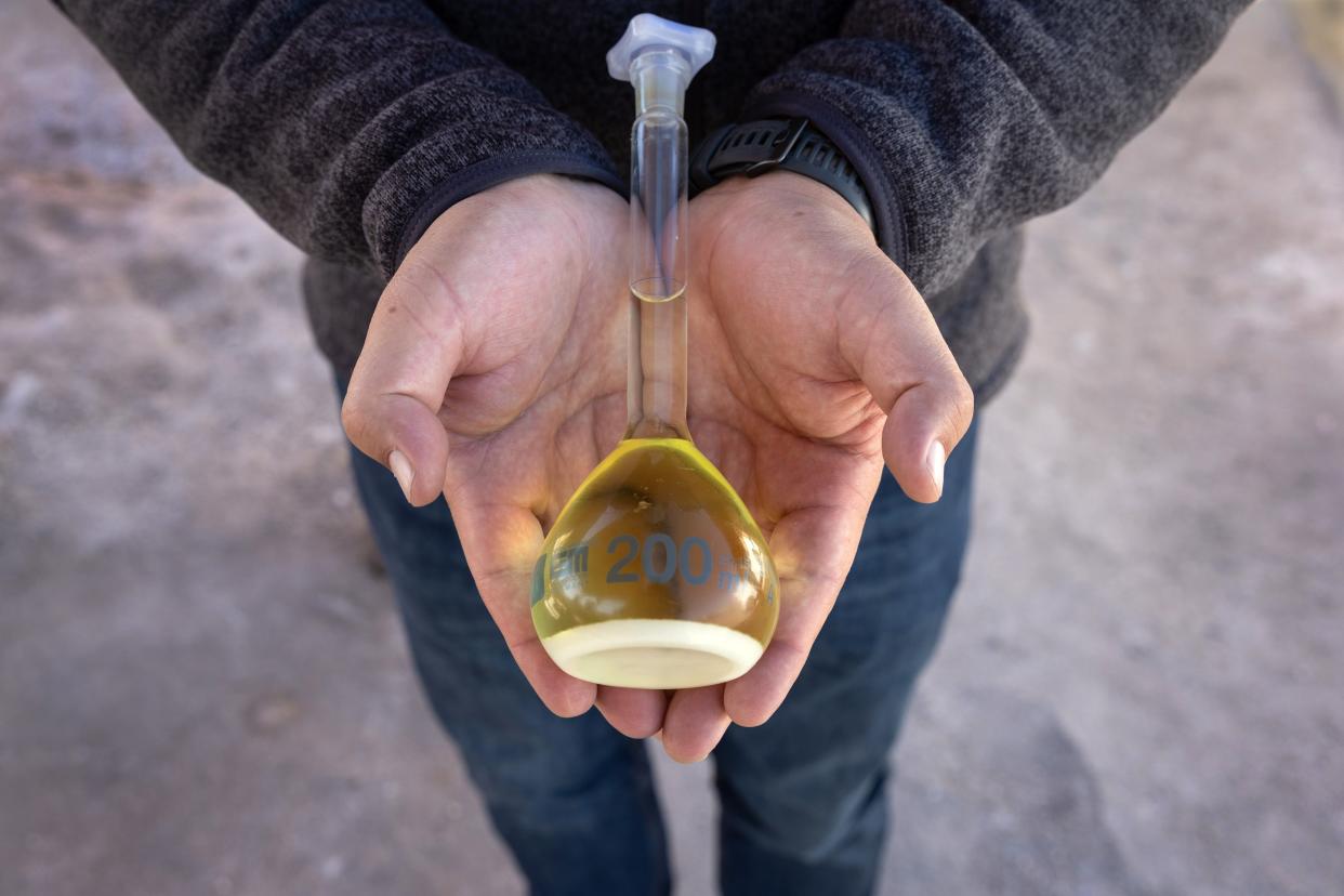 Albemarle Corp. spokesman Marcelo Valdebenito holds a bottle of liquid lithium carbonate at a lithium mine on Aug. 24 in Salar de Atacama, Chile.