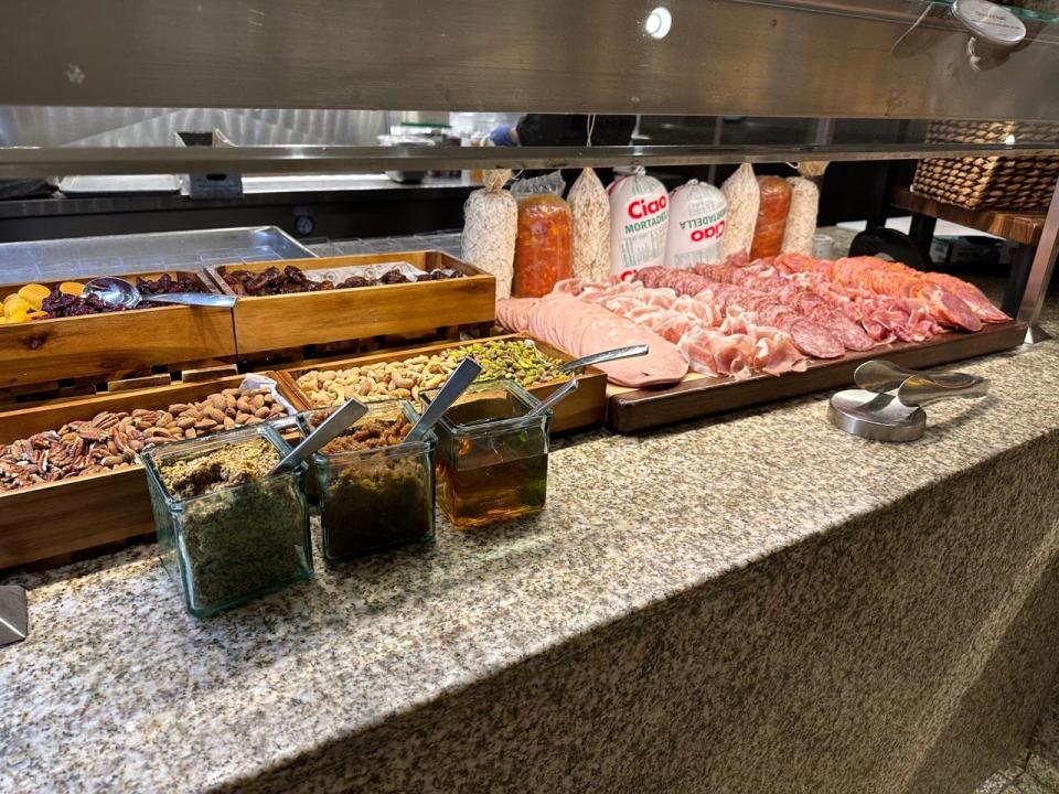 Display of cold cut meats on cutting board next to stacks of trays of nuts at Bacchanal buffet