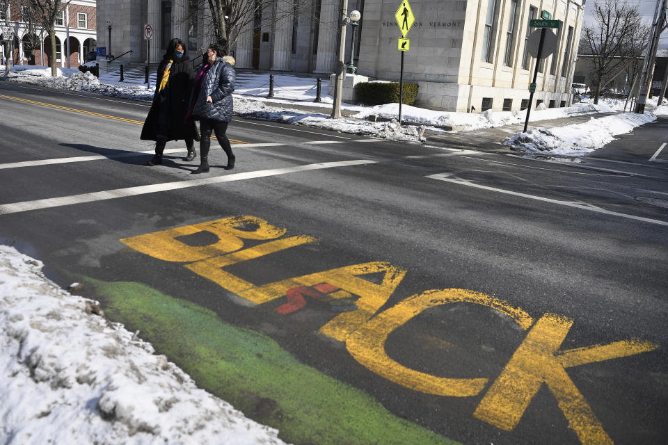 In this Saturday, Feb. 20, 2021, photo, Mia Schultz, president of the Rutland area branch of the NAACP, right, walks with town Select Board candidate Tina Cook past a Black Lives Matter mural on a street in Bennington, Vt. A number of protesters, including some who carried an anti-Black Lives Matter sign, stood in the way during painting of the mural, forcing those working on the mural to paint around their feet and bodies blocking the letters. Cook came up short in the March 2 election in her effort to become the first African American elected to the board. (AP Photo/Jessica Hill)