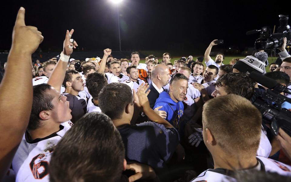 Bremerton assistant football coach Joe Kennedy, at center in blue, is surrounded by Centralia High School football players after they took a knee and prayed with him on the field after the team's game against Bremerton on Oct. 16, 2015, in Bremerton, Wash.