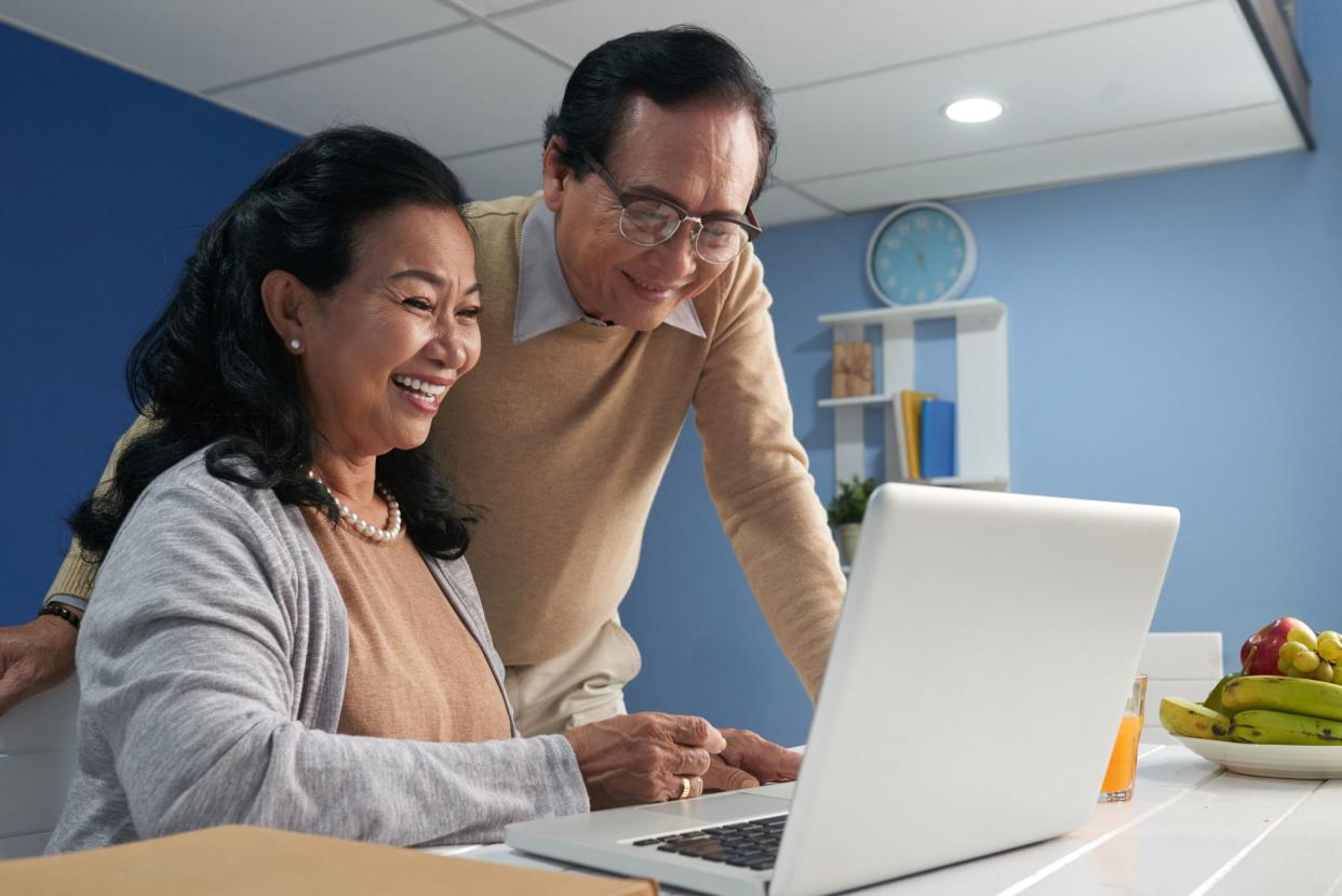 Laughing senior couple watching something funny on laptop