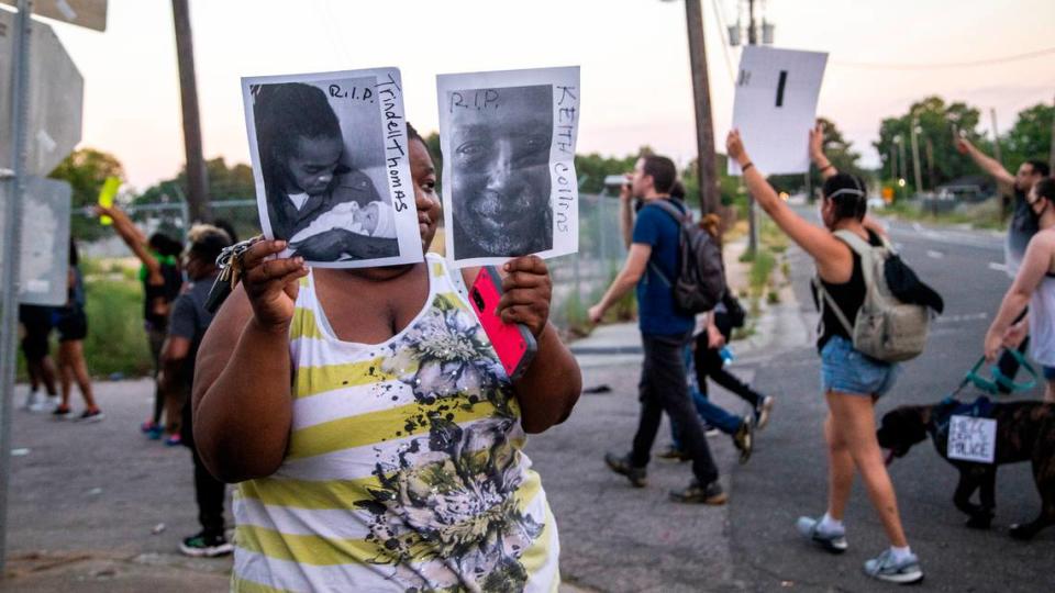 Nichole Wilders holds photos of Trindell Thomas and Keith Collins who both died during incidents with Raleigh Police as demonstrators march near the intersection of South Blount and Bragg Streets during a protest against police misconduct and systemic racism In Raleigh Sunday, June 7, 2020.