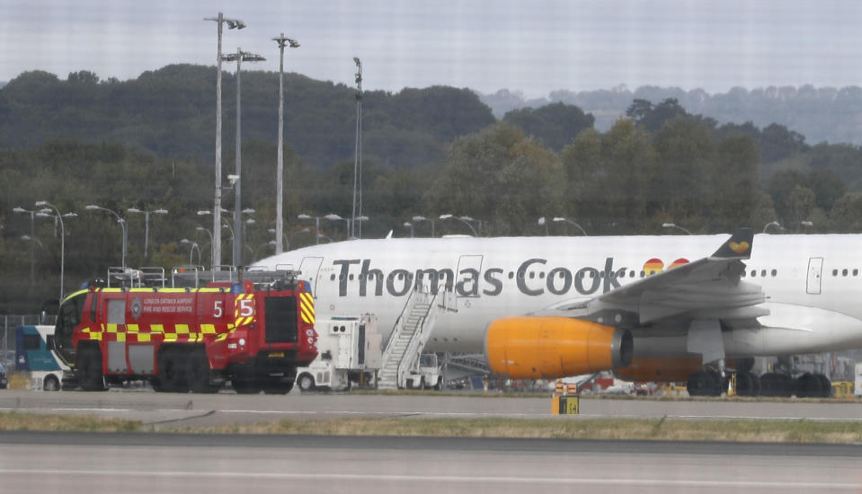 An airport fire engine passes by a Thomas Cook aircraft on the ground at Gatwick Airport, England, Monday, Sept. 23, 2019. British tour company Thomas Cook collapsed early Monday after failing to secure emergency funding, leaving tens of thousands of vacationers stranded abroad. (AP Photo/Alastair Grant)