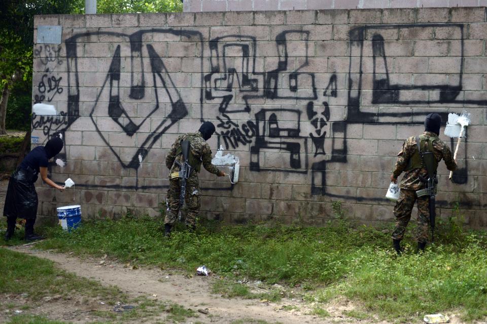 Police officers and soldiers paint over graffiti associated with the Mara Salvatrucha gang, or MS-13, in&nbsp;Quezaltepeque, El Salvador. (Photo: Marvin Recinos/AFP/Getty Images)