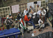 Indian farmers sit on their tractors after arriving at the Delhi-Uttar Pradesh border for Tuesday's tractor rally in New Delhi, India, Monday, Jan. 25, 2021. Thousands of farmers gathered on the borders of Delhi for a massive tractor rally on Tuesday against the three contentious farm laws when India will celebrate its Republic day with a military and cultural parade. The two-month-old old blockade of highways connecting the capital with the country's north continues as the talks have remained deadlocked with the government refusing to scrap the new agricultural reform laws which the farmers say will benefit large corporations. (AP Photo/Manish Swarup)