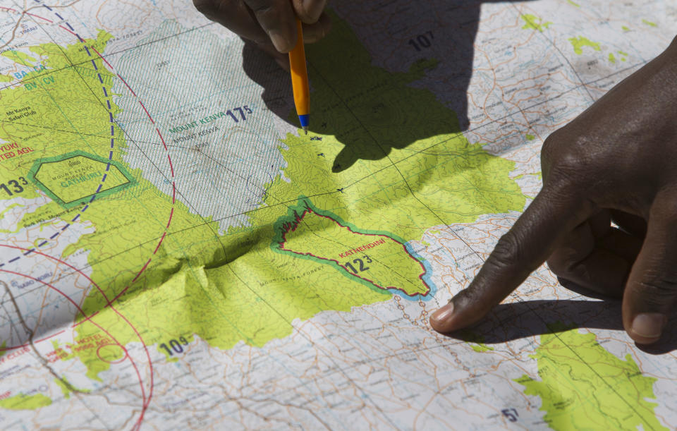 Members of the Kenyan Wildlife Service point to locations of fires on a map as they discuss their strategy to put out forest fires on the slopes of Mount Kenya, the second-highest peak in Africa at 5,199 meters (17,057 feet), in Kenya Tuesday, March 20, 2012. Fires that have been raging across Mount Kenya may have been set by poachers trying to create a diversion from their illegal attacks on animals, a wildlife official said Tuesday. (AP Photo/Ben Curtis)