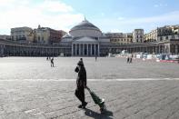 A person wearing a respiratory mask as part of precautionary measures against the spread of the new COVID-19 coronavirus, walks across a deserted Piazza del plebiscito in Naples on March 10, 2020. (Credit: Carlo Hermann/AFP)