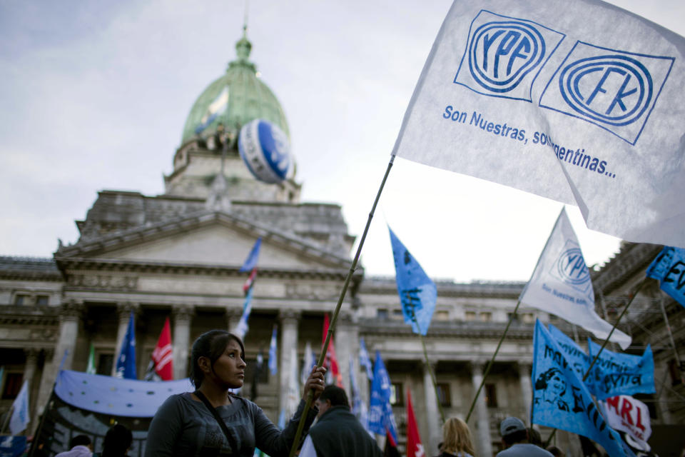 A woman holds a flag that reads in Spanish "YPF CFK are ours, they are Argentina's" outside Congress as lawmakers debate the YPF bill on the expropriation of the oil company in Buenos Aires, Argentina, Thursday, May 3, 2012. President Cristina Fernandez, who pushed forward a bill to renationalize the country's largest oil company, said the legislation put to congress would give Argentina a majority stake in the oil and gas company YPF by taking control of 51 percent of its shares currently held by Spain's Repsol. (AP Photo/Natacha Pisarenko)