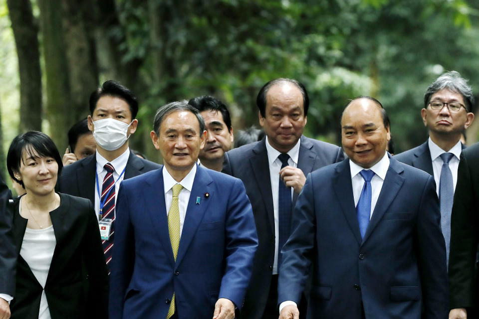 Japanese Prime Minister Yoshihide Suga, center left, and his Vietnamese counterpart Nguyen Xuan Phuc, center right, visit the late President Ho Chi Minh's Stilt House in Hanoi, Vietnam, Monday, Oct. 19, 2020. Suga is on an official visit to Vietnam. (AP Photo/Minh Hoang, Pool)