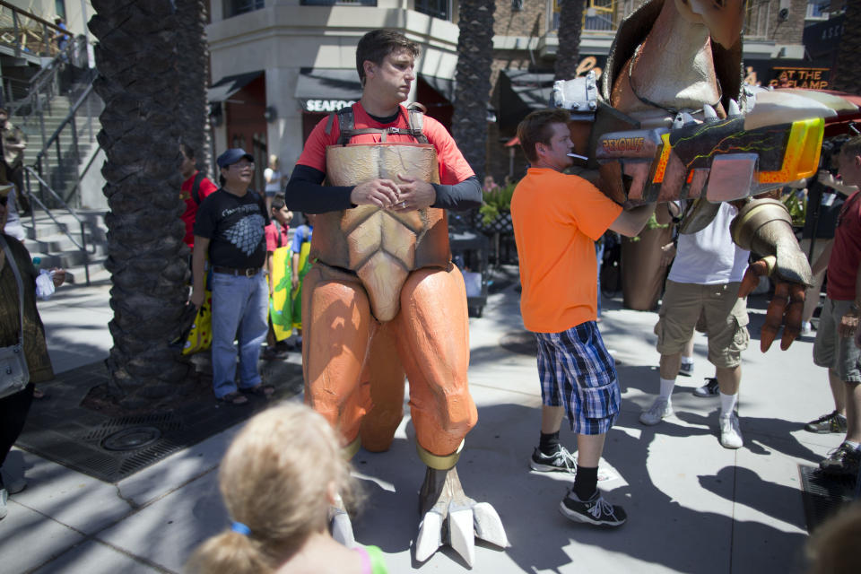 Chris Rose puts on his suit, a new comic book character named Rexodus during Comic-Con Thursday, July 24, 2014, in San Diego. Thousands of fans with four-day passes to the sold-out pop-culture spectacular flocked to the event Thursday, many clad in costumes. (AP Photo)