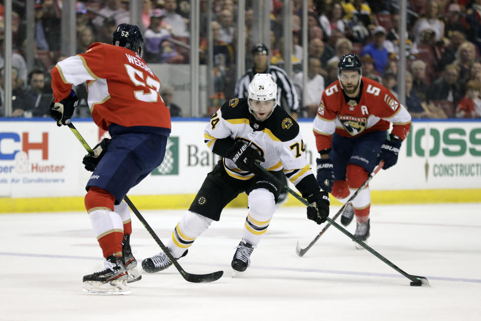 Boston Bruins left wing Jake DeBrusk (74) takes the puck down the ice against Florida Panthers defensemen MacKenzie Weegar (52) and Aaron Ekblad (5) during the first period of an NHL hockey game, Thursday, March 5, 2020, in Sunrise, Fla. (AP Photo/Wilfredo Lee)