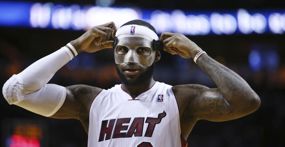 Miami Heat's LeBron James adjusts his protective mask during the first half of an NBA basketball game in Miami, Monday, March 3, 2014 against the Charlotte Bobcats. (AP Photo/J Pat Carter)