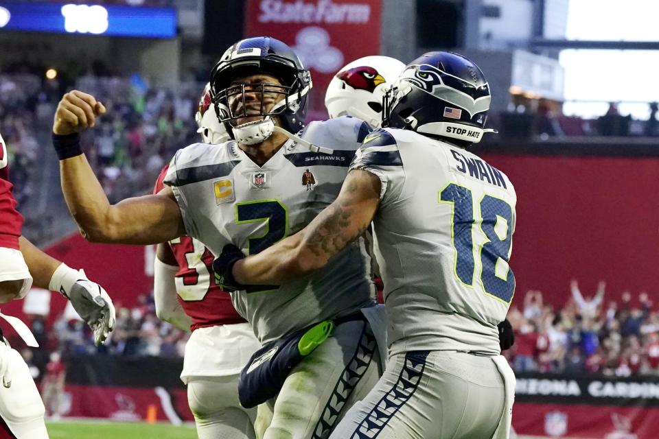 Seattle Seahawks quarterback Russell Wilson, left, celebrates his touchdown run against the Arizona Cardinals with Seattle Seahawks wide receiver Freddie Swain (18) during the second half of an NFL football game Sunday, Jan. 9, 2022, in Glendale, Ariz. (AP Photo/Darryl Webb)