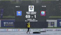 A ground staff member walks on the covered field of Galle International Cricket Stadium ground after the rain interrupted the play during the day two of the second test cricket match between Sri Lanka and West Indies in Galle, Sri Lanka, Tuesday, Nov. 30, 2021. (AP Photo/Eranga Jayawardena)