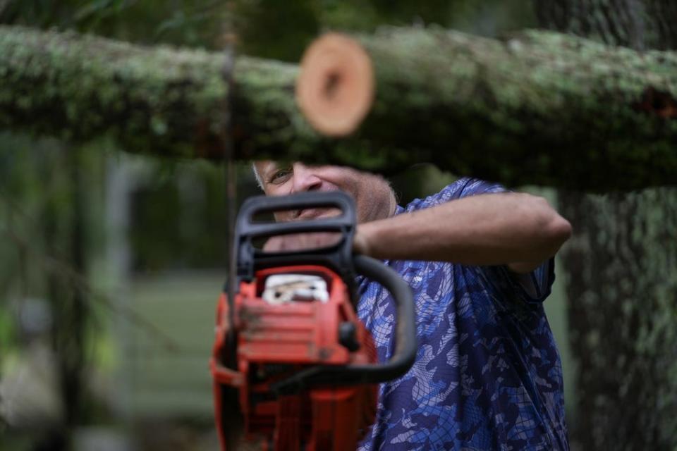 Aug 30, 2023; Perry, FL, USA; Frank Houck uses a chainsaw to cut down fallen tree limbs from a neighbor's home in Perry, Florida, Wednesday. Hurricane Idalia landed along Florida’s Big Bend area, leaving some homes and businesses destroyed. Mandatory Credit: Megan Smith-USA TODAY