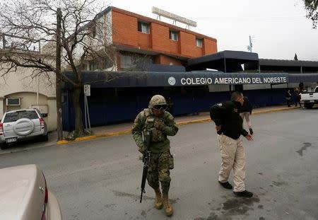 A soldier and a police officer walk outside the Colegio Americano del Noreste after a student opened fire at the American school in Monterrey, Mexico January 18, 2017. REUTERS/Daniel Becerril