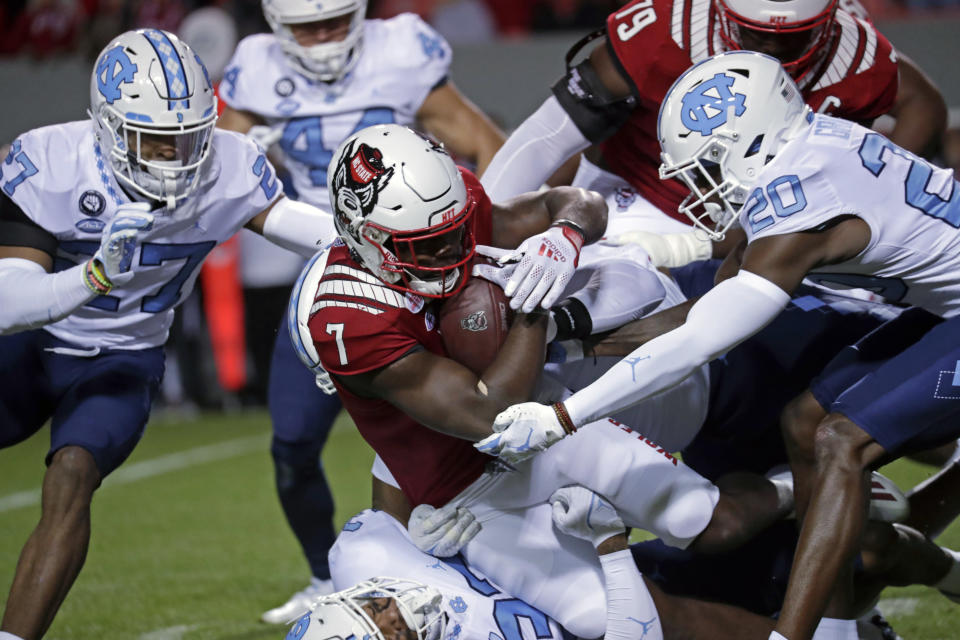 North Carolina State running back Zonovan Knight (7) gets tackled by North Carolina defensive back Giovanni Biggers (27) and defensive back Tony Grimes (20) during the first half of an NCAA college football game Friday, Nov. 26, 2021, in Raleigh, N.C. (AP Photo/Chris Seward)