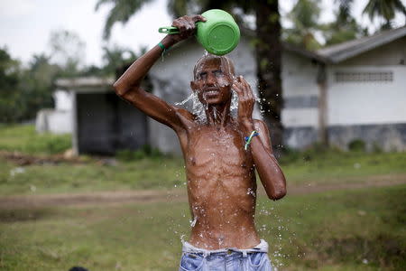 A Rohingya migrant, who recently arrived in Indonesia by boat, takes a bath after a haircut inside a temporary compound for refugees in Aceh Timur regency, Indonesia's Aceh Province May 22, 2015. REUTERS/Beawiharta