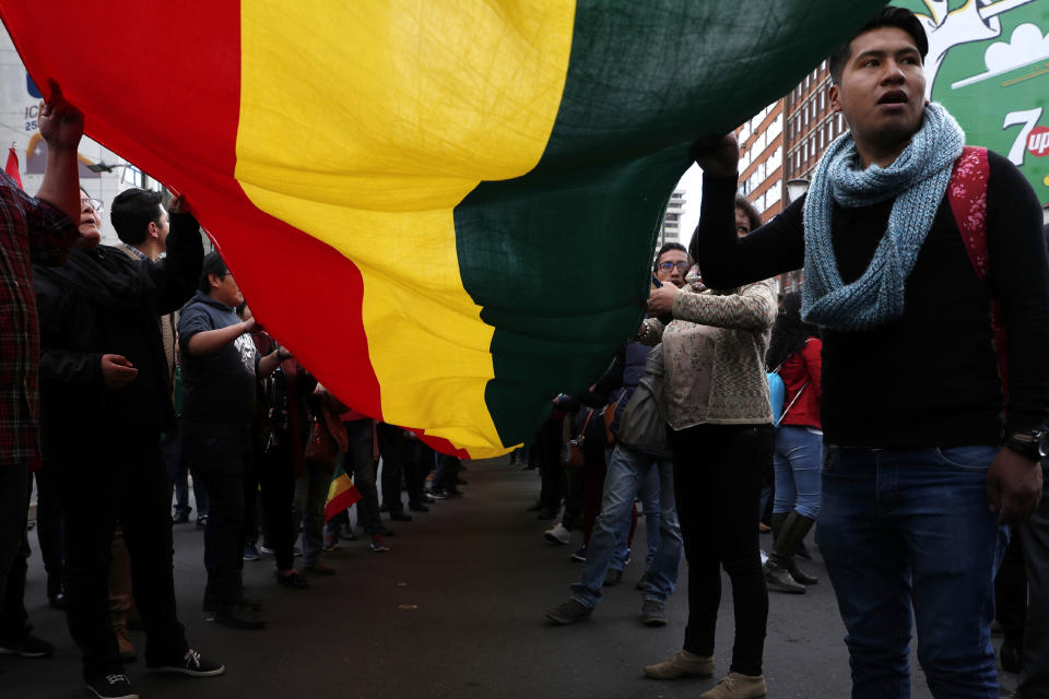 Anti-government protesters march with a giant national flag demanding a second round for the presidential race, in La Paz, Bolivia, Thursday, Oct. 24, 2019. Bolivia's Evo Morales declared himself the outright winner Thursday of an election in which he was seeking a fourth term as president, enraging his opponents who alleged vote fraud and called for further protests to demand a second round of voting.(AP Photo/Juan Karita)