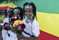 Children hold flowers to greet the arrival of Ethiopia's Prime Minister Abiy Ahmed, ahead of a final campaign rally, in the town of Jimma in the southwestern Oromia Region of Ethiopia Wednesday, June 16, 2021. The country is due to vote in a general election on Monday, June, 21, 2021. (AP Photo/Mulugeta Ayene)