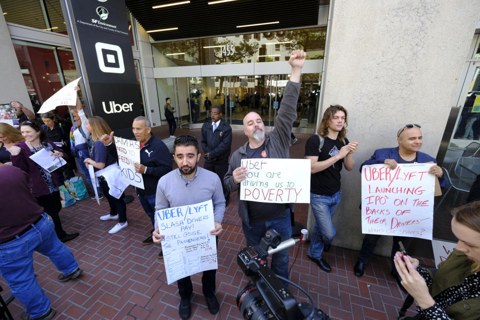 FILE - In this May 8, 2019, file photo Uber and Lyft drivers carry signs during a demonstration outside of Uber headquarters in San Francisco. A California law that makes it harder for companies to treat workers as independent contractors takes effect next week, forcing small businesses in and outside the state to rethink their staffing. (AP Photo/Eric Risberg, File)
