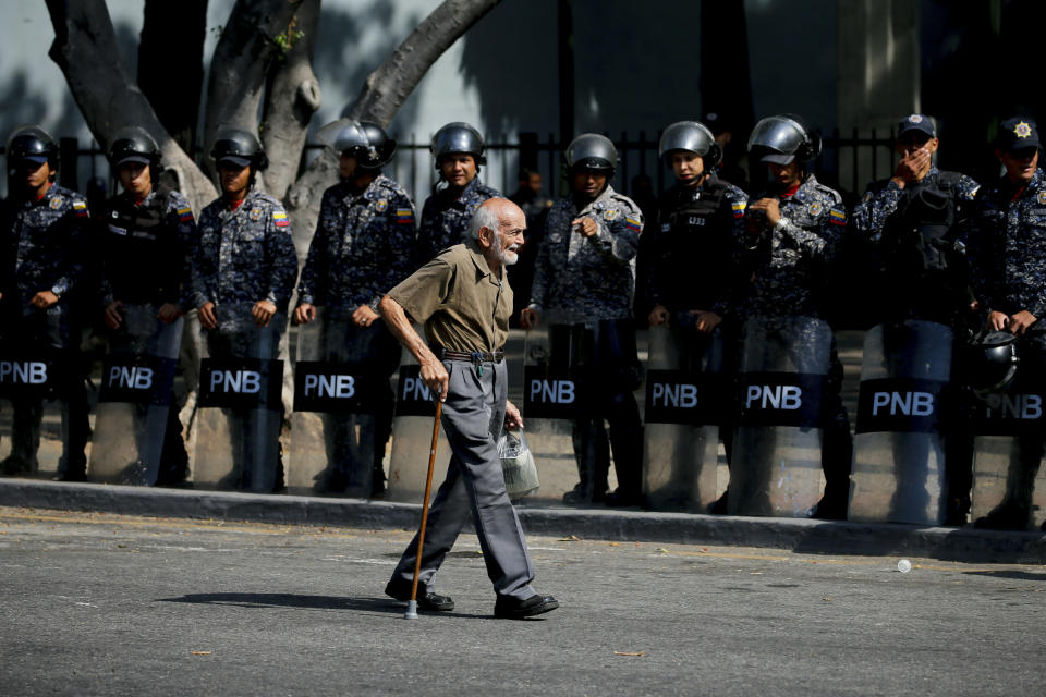 Police stand guard in anticipation of a march called by a coalition of opposition parties and civic groups who are petitioning lawmakers for a law of guarantees that will protect workers who have been victims of political retaliation and unjustified dismissals, in Caracas, Venezuela, Tuesday, March 19, 2019. (AP Photo/Fernando Llano)