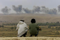 <p>Two Northern Alliance soldiers watch as the dust and smoke rises afterexplosions in Taliban positions on Kalakata hill, near the village of Ai-Khanum in northern Afghanistan, Nov. 1, 2001. (Photo: Vasily Fedosenko/Reuters) </p>