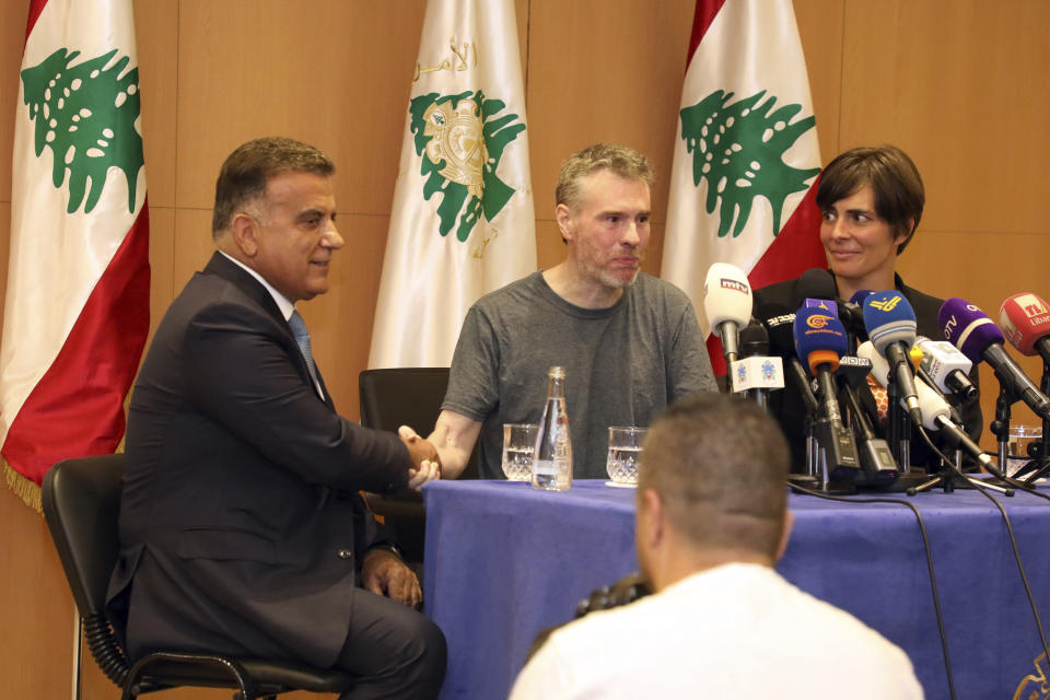 This handout photo by the Lebanese General Security Directorate, shows Maj. Gen. Abbas Ibrahim, left, Lebanon's General Security Chief, shaking hands with Canadian citizen Kristian Lee Baxter, center, who was released from Syrian prisons to Lebanon, during a press conference in Beirut, Lebanon, Friday, Aug 9, 2019. Baxter held in Syrian prisons since last year and freed after Lebanese mediation said Friday he had no idea if anyone knew he was still alive. The Lebanese general who mediated his release said Baxter was heading home. It was not clear when Baxter was released from Syria. (The Lebanese General Security Directorate via AP)