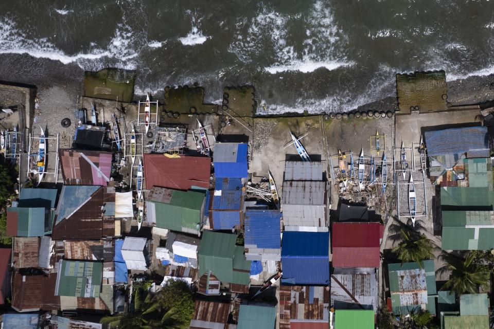 Small fishing boats are docked beside homes as waves batter the coastal village of Simlong in Batangas province, Philippines on Tuesday, Aug. 8, 2023. The Philippines is seeing one of the world's biggest buildouts of natural gas infrastructure. This could impact nearby coral reefs and fishing communities. (AP Photo/Aaron Favila)
