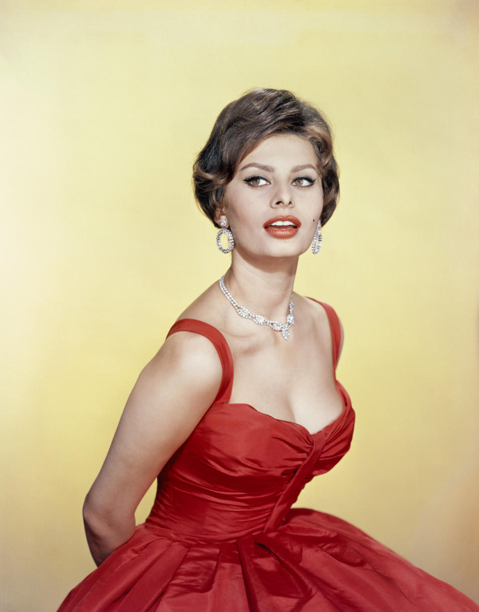 Posing for a photo in a red dress,&nbsp;circa 1955.