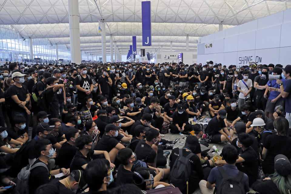 Protesters gather near an information board during a protest at the Hong Kong International Airport, Monday, Aug. 12, 2019. One of the world's busiest airports canceled all flights after thousands of Hong Kong pro-democracy protesters crowded into the main terminal Monday afternoon. (AP Photo/Kin Cheung)