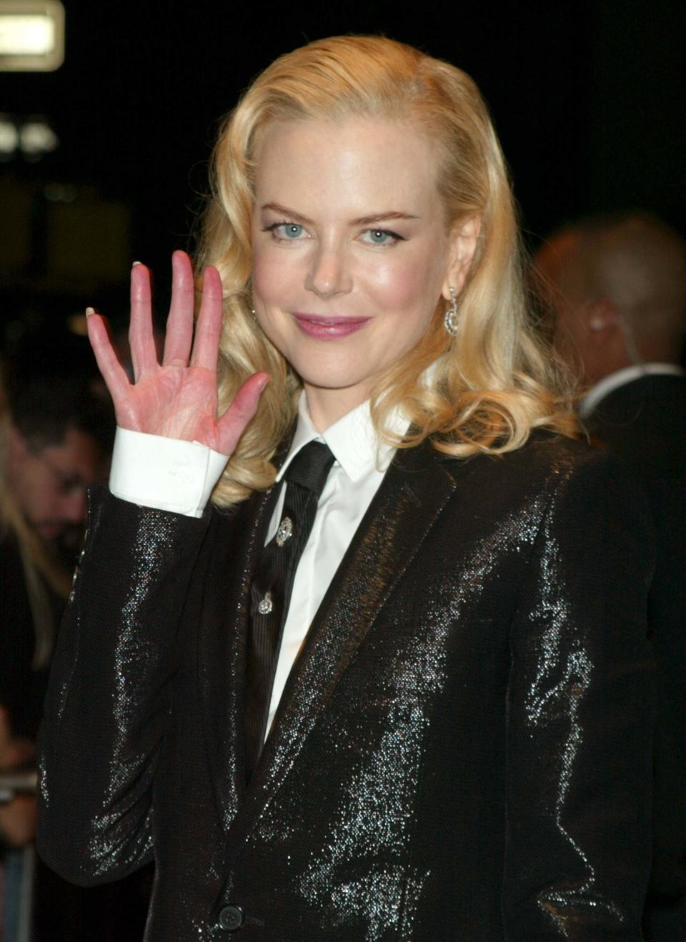 Nicole waving and wearing a shiny jacket