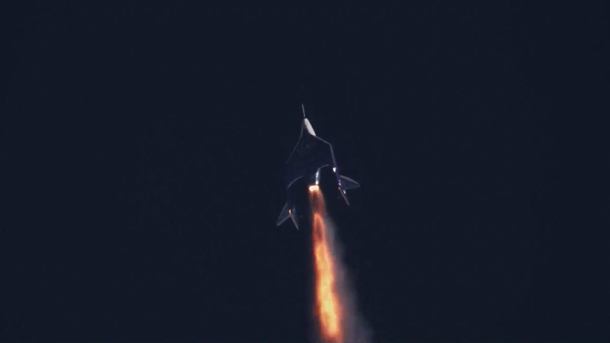  A space plane fires its rocket engine against a dark sky. 