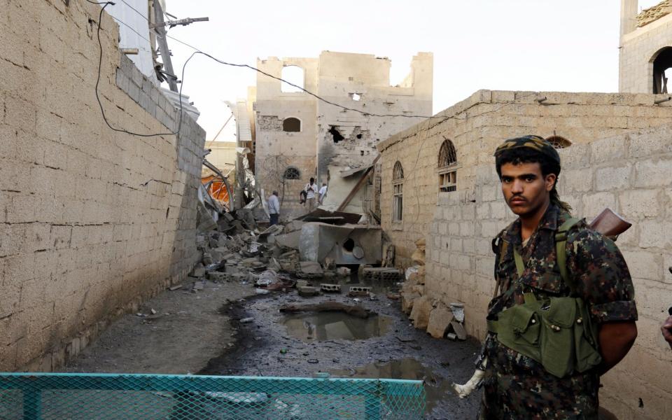 Houthi militiaman keeps watch as others inspect destroyed houses after an alleged Saudi-led airstrike targeted a neighborhood in Sana'a, Yemen, - Credit: EPA