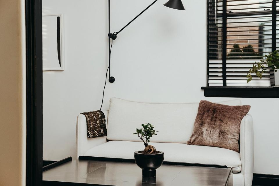 White sofa with faux fur pillow and brown blanket draped over the arm