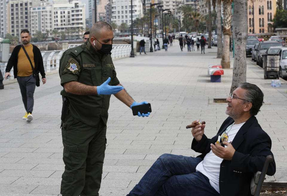 CAPTION CORRECTION:CORRECTS BYLINE - A municipal police officer, left, orders a man to leave the corniche, or waterfront promenade, along the Mediterranean Sea, as the country's top security council and the government were meeting over the spread of coronavirus, in Beirut, Lebanon, Sunday, March 15, 2020. Lebanon has been boosting precautionary measures including halting flights from several countries, closing all restaurants and nightclubs and tightening measures along the border with neighboring Syria. (AP Photo/Hussein Malla