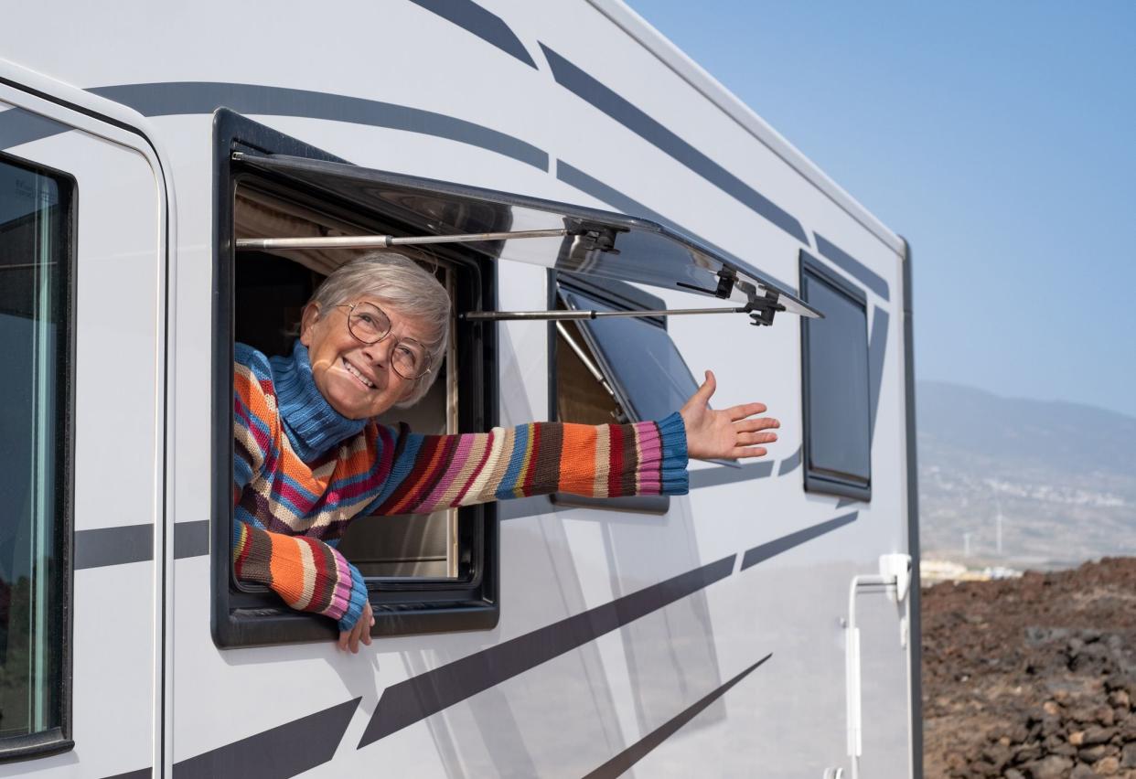 Travel and transport concept. Senior smiling woman at the window of the motorhome camper van enjoying road trip and vacation