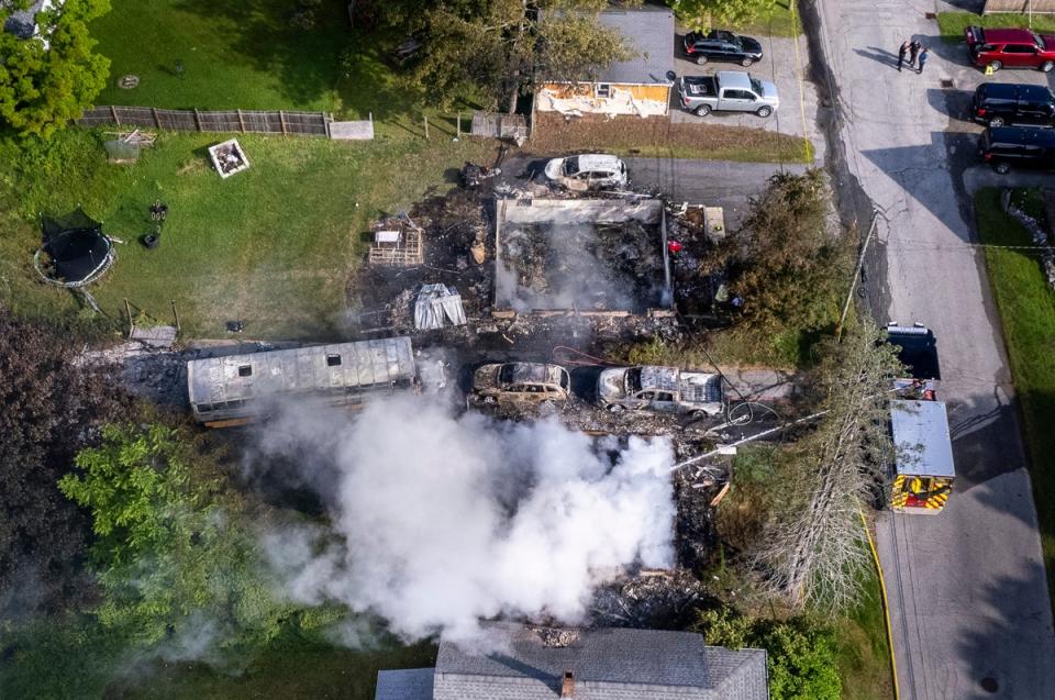 Auburn firefighters hose down the remains of a home in Auburn, Maine, early Saturday after a police shooting. The suspect was recently released on bail (AP)