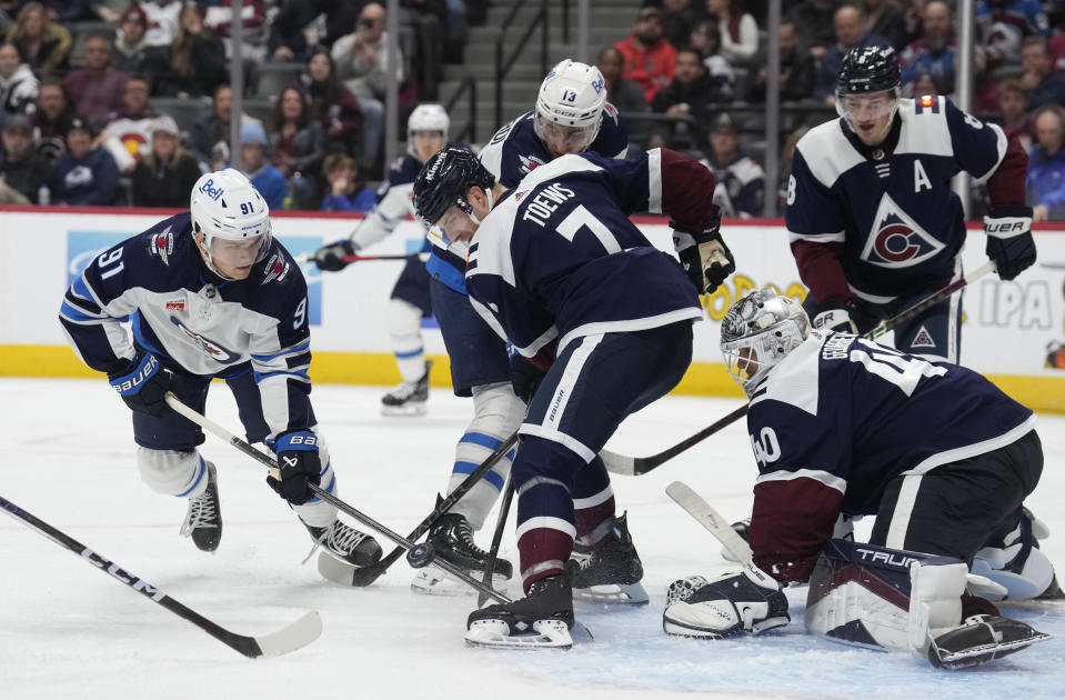 Winnipeg Jets center Cole Perfetti, left, tries to corral the puck as Colorado Avalanche defenseman Devon Toews (7) jostles with Winnipeg Jets center Gabriel Vilardi for position in front of Colorado goaltender Alexandar Georgiev during the second period of an NHL hockey game Thursday, Dec. 7, 2023, in Denver. (AP Photo/David Zalubowski)