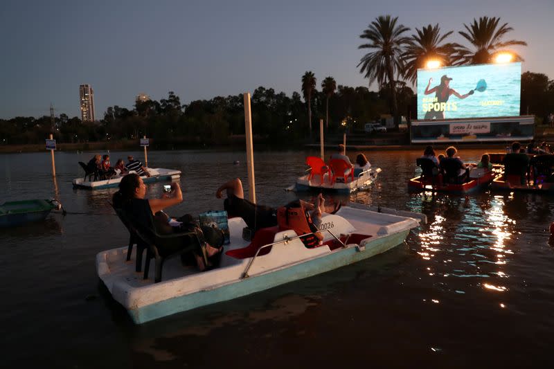 Personas se sientan en botes mientras ven la proyección de una película durante una prueba para los miembros de los medios de comunicación del cine flotante del municipio de Tel Aviv, en el lago navegable del parque HaYarkon en Tel Aviv, Israel 20 de agosto de 2020.