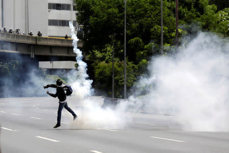 A demonstrator throws a tear gas canister during a rally against Venezuela's President Nicolas Maduro in Caracas, Venezuela, May 26, 2017. REUTERS/Marco Bello