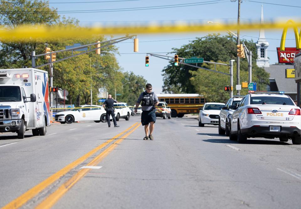 An Indianapolis Metro Police Officer walks down 10th St. after a shooting that saw one person killed Friday, Sept. 30, 2022, in Indianapolis. The shooting occurred outside of a barbershop at the 4600 block of East 10th St. and North Bosart Ave. 