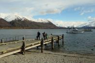 People walk on a jetty at Lake Wanaka in Wanaka, New Zealand.