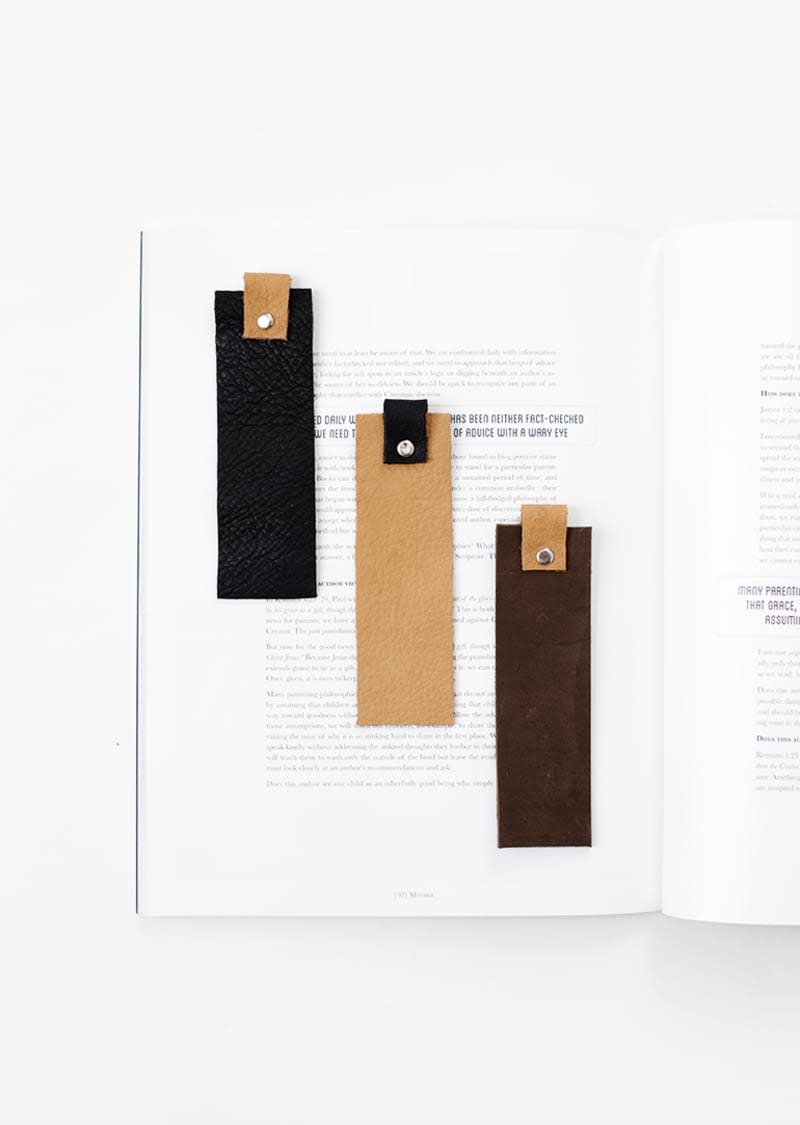 Three two-tone leather bookmarks against the page of a book.