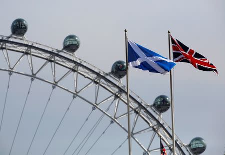 A Scottish Saltire flag and British Union flag fly together with the London Eye behind in London September 19, 2014. REUTERS/Luke MacGregor