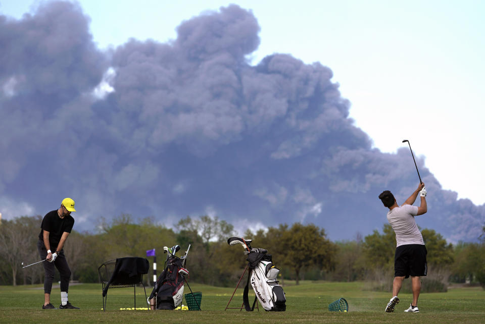 Golfers practice at the Battleground Golf Course driving range as a chemical fire at Intercontinental Terminals Company continues to send dark smoke over Deer Park, Texas, on, March 19, 2019. (Photo: ASSOCIATED PRESS)