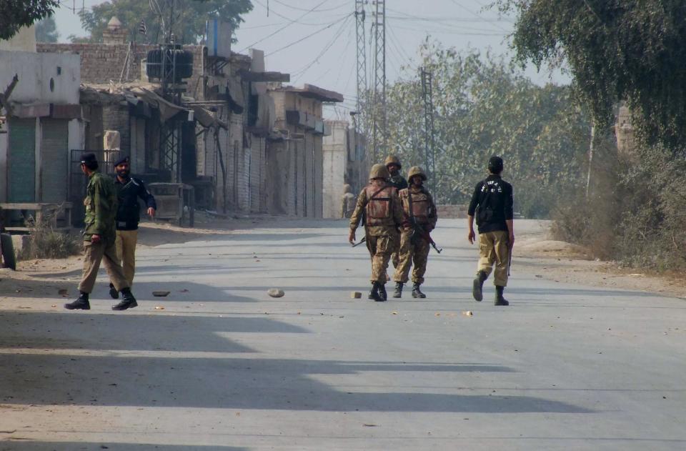 Pakistani police and army soldiers stand guard on a road leading to the site of bomb explosion in Bannu, Pakistan on Sunday Jan. 19, 2014. A regular Sunday morning troop rotation going into the Pakistani tribal region of North Waziristan was shattered by an explosion that killed tens of people, mostly paramilitary troops. The Pakistani Taliban claims responsibility for placing the bomb on one of the trucks hired for the job. (AP Photo/Ijaz Muhammad)